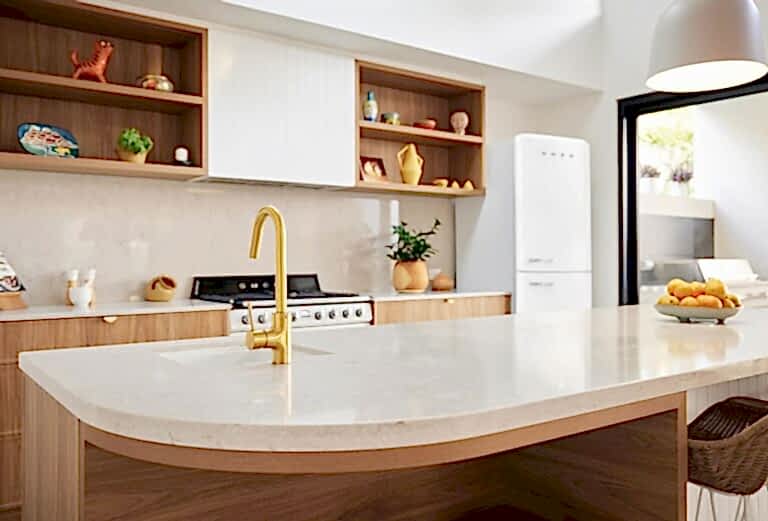 Modern custom home kitchen interior with timber cabinetry, stone island bench and brass tapware by Coast Homes